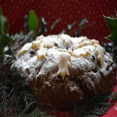 Christmas Soda Bread with holly and ivy marzipan decoration and real green holly leaves in the background.